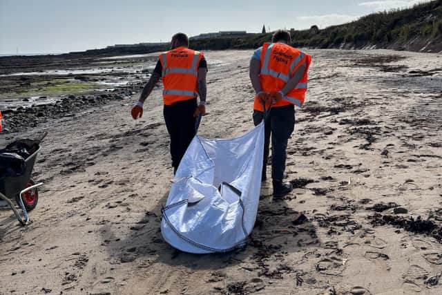 Offenders move the heavy industrial waste off the beach.