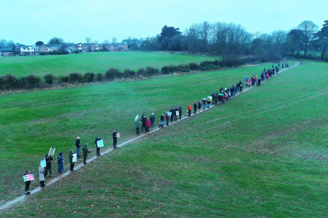 Protesters walk the public footpath across the site of the proposed 170 homes
