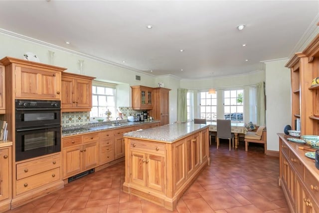 A large 24-foot family kitchen with fitted range of floor and wall units and bay window with a seating area.