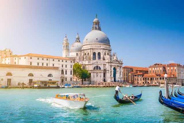 Beautiful view of the traditional gondola on the Grand Canal with the historic Basilica Santa Maria della Salute in the background on a sunny day in Venice, Italy