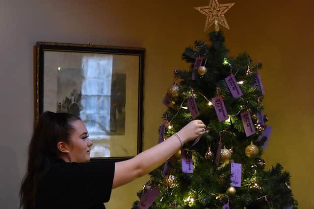A staff member hanging the tags on the tree.