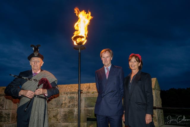 The beacon lighting on the roof of Alnwick Castle with the Duke and Duchess of Northumberland and the Duke's piper, Richard Butler.