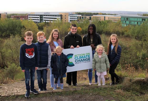 Young people holding the council’s new Action on Climate Change logo, which will be launched during COP26, in Silverlink Biodiversity Park.