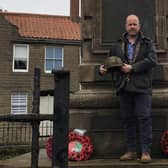Jim Carnegie at Berwick War Memorial holding the helmet that he wore throughout the battle. Picture by Alan Hughes.