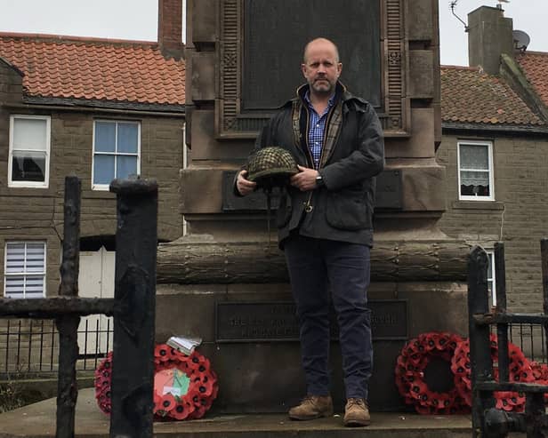 Jim Carnegie at Berwick War Memorial holding the helmet that he wore throughout the battle. Picture by Alan Hughes.