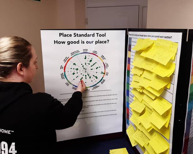 An event attendee contributing to the Place Standard tool. They are applying a sticky dot to indicate how much they approve or disapprove of certain elements of Bedlington.