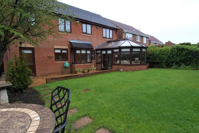 The rear garden includes decorative paving providing a patio area, tree borders and an additional paved terrace area.