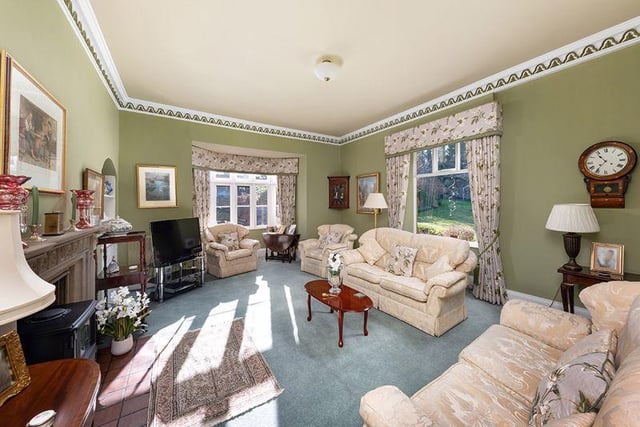 A magnificent drawing room with stone fireplace and dual aspect windows overlooking the garden.