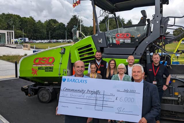 Councillors, council staff and staff from DSD Construction with a cheque for £6,000 for community benefits secured through the council's contracts work. In the background is DSD Constcruction's "Wellbeing Machine".