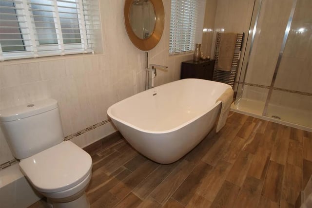 The family bathroom is furnished with a modern white suite, incorporating a contemporary style free standing bath and double shower enclosure.
