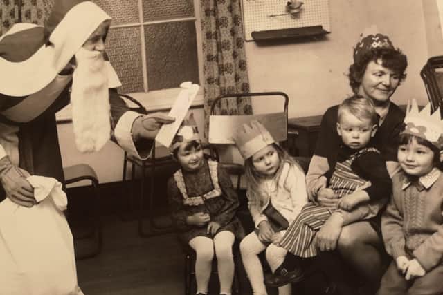 Molly Cooper, with her son Adam on her knee and daughter Rachel, far left, at St James' church play group Christmas party, 1975.
