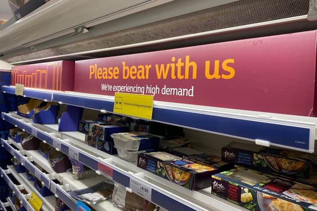 A shelf sign in Sainsbury's, Alnwick, in August 2021, warning: 'Please bear with us. We are experiencing high demand.'