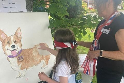 A young girl has a go at the 'pin the tail on the Corgi' game.