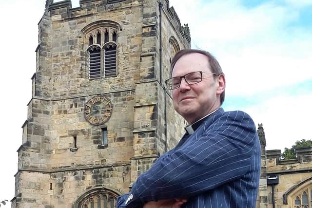 Rev Canon Paul Scott standing in front of the bell tower of St Michael's Church.