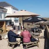 The beer garden at The Jolly Fisherman in Craster with Dunstanburgh Castle in the distance.