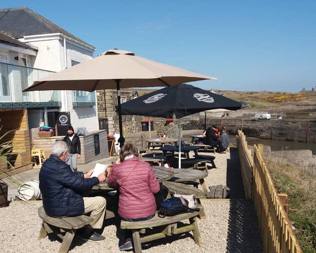 The beer garden at The Jolly Fisherman in Craster with Dunstanburgh Castle in the distance.