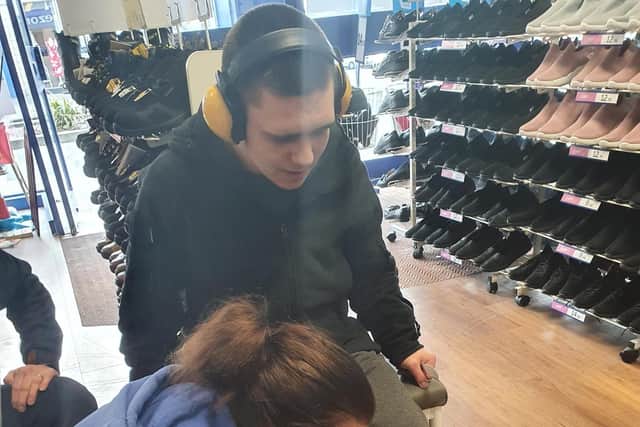 Katie helps Luke to get measurements for shoes at a shoe shop.