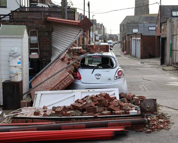 A car stands under a pile of bricks after a wall collapsed onto the vehicle overnight.