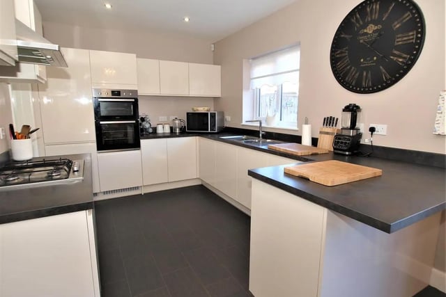 The kitchen features a range of wall and floor mounted units, integrated appliances and an adjoining utility room.