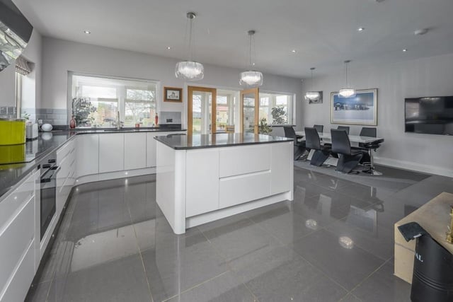 The impressive kitchen/diner has a superb number of white high gloss wall and base units complemented by a stylish black sparkly granite work surface. The large centre island has a matching work surface.