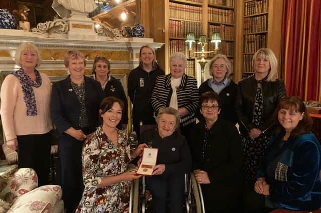 Lucinda Porter surrounded by friends, receives her British Empire Medal from the Duchess of Northumberland.