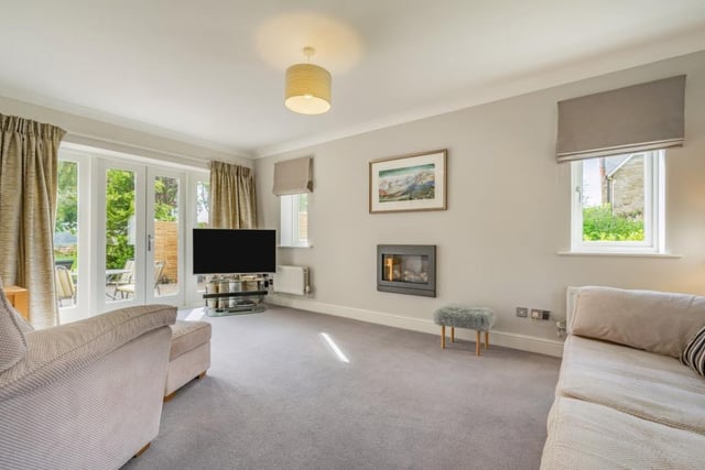The triple aspect sitting room, which features a log-effect fireplace and French doors opening onto the rear garden.