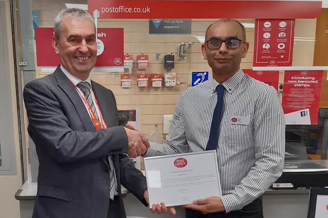 Postmaster Paul Gill receives leaving gifts from Post Office area manager Neil Barnard.