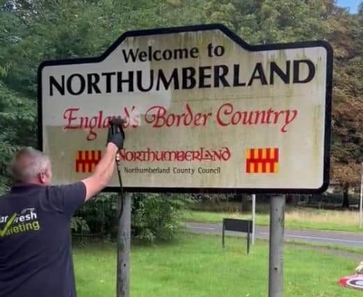 Andrew Newton giving a 'Welcome to Northumberland' sign a good clean.