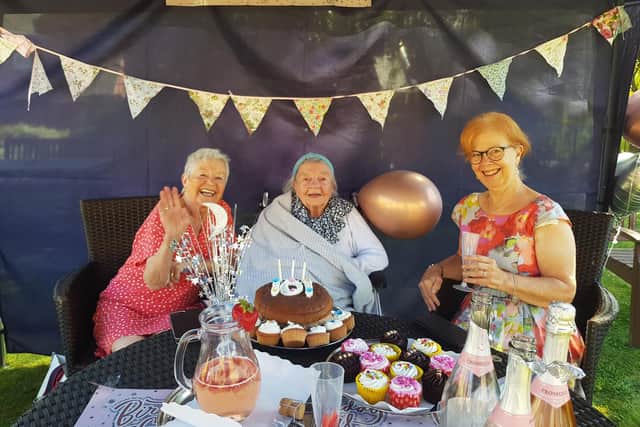 Care home resident Jen Bell sits around the table alongside friends and family as they prepare to enjoy the cake.