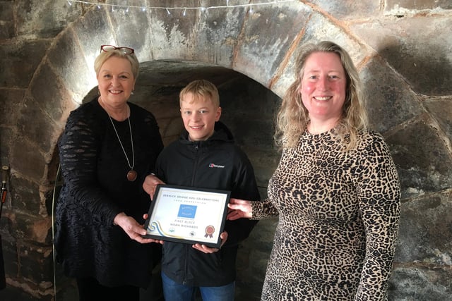 Anne Humphrey (left) and Lindsay Benton (right) present Noah with his award certificate. Picture by Canon Alan Hughes.