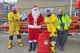 Seahouses RNLI's Graeme Trotter, Iain Saunders and John Parkin assist Santa with his bag of presents. Picture: Seahouses RNLI
