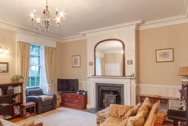 Drawing room with sash windows overlooking the garden and a cast iron wood burning stove set into a period fireplace.