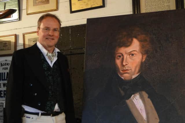 Andrew Ayre, chairman of the Wilson's Tales Project, with a portrait of John Mackay Wilson.