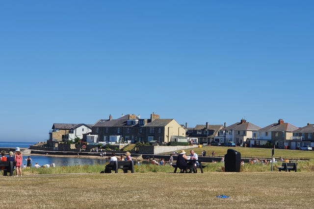 People sat on benches, tables and even the grass as they enjoyed Amble's glorious sunshine.