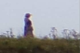 Close up: A magnified picture of the person spotted walking behind the family. She appears to be in old-fashioned clothes, wearing a hat and carrying a bag.