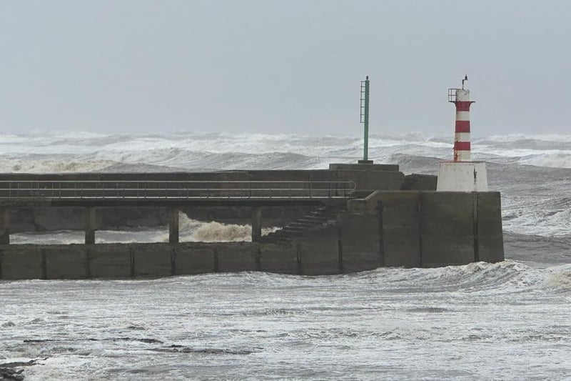 Waves crashing against the pier in Amble.