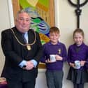 Coun David Bawn with pupils from Morpeth All Saints Church of England First School holding their commemorative mugs.
