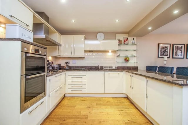 The kitchen provides a range of integrated appliances, units and a large breakfast bar, with a utility room connected.