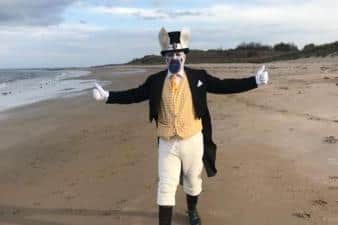 John Young on the beach dressed as the White Rabbit from Alice in Wonderland.