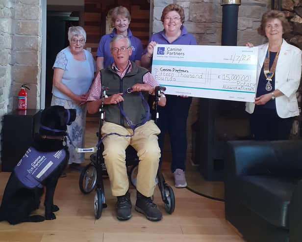 Joy and Susan hold the large cheque with Mary Nisbet, Canine Partner James Babington Smith, his canine friend Spud and volunteer Judith Thurland.