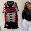 Student artist Phoebe Gamblin poses next to her away kit design.