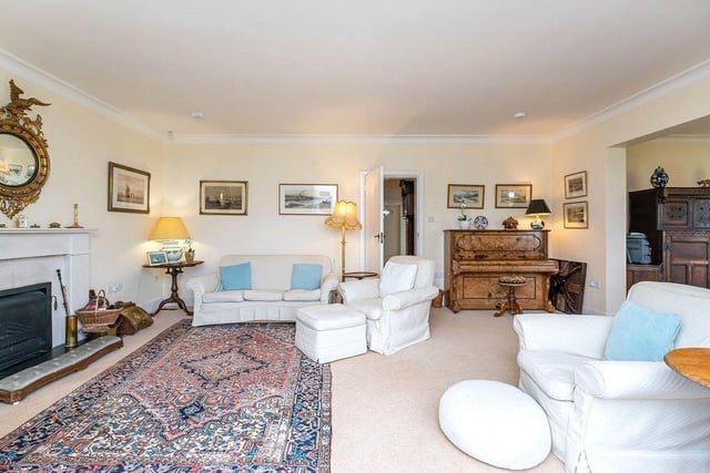A comfortable and well proportioned sitting room with open fire place, large windows and doors opening directly into the garden.