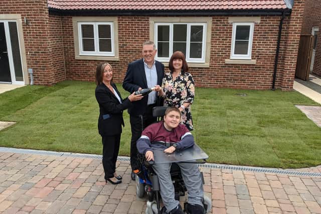 Lynn Grant of WalkersXchange, left, presents David and Trudi Carpenter, with son Adam, with a bottle of champagne to mark their final site visit before moving in later this month.