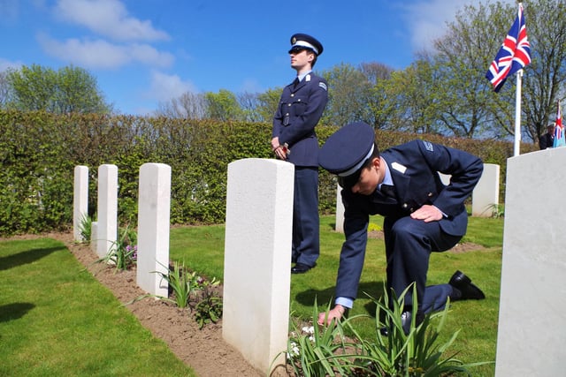 A member of the University Air Squadron places a cross on the grave of an ANZAC airman.