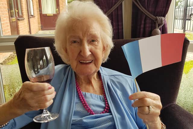 A resident at Station Court Care Home sips wine and waves the French flag.