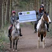 Alex Sinclair and Danielle McKinnon from Eat, Sleep, Ride on their horses, Ares and Ace, and with the cheque from the Fallago Environment Fund. Picture by Paul Dodds.