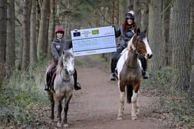 Alex Sinclair and Danielle McKinnon from Eat, Sleep, Ride on their horses, Ares and Ace, and with the cheque from the Fallago Environment Fund. Picture by Paul Dodds.