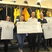 Staff from The Amble Inn present RNLI crew members with a £1,000 donation.