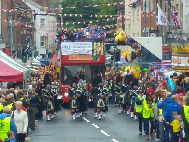 Hundreds of people line the streets to cheer on Morpeth Town FC's open top bus parade as part of Morpeth Fair Day.