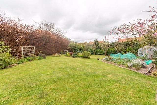 Private mature gardens surround the house, including a substantial lawned area.